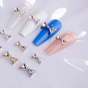 Macro view of bow-shaped nail art charms with K9 triangle crystals and metal bases