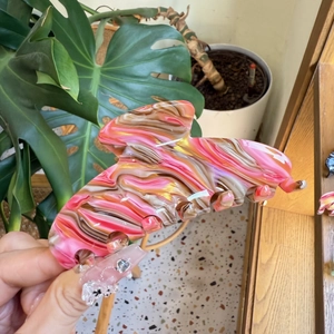 Pink marble acetate hair claw clip with a unique glossy swirl pattern held by hand