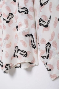 Detail of white chiffon shirt with pink paisley print and black cowboy boot patterns