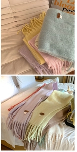 Close-up of soft pastel cashmere-like scarves with fringe and leather tags on sofa