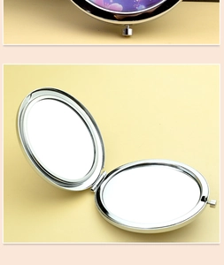 Detail view of round metal folding makeup mirror with double-sided design and polished finish