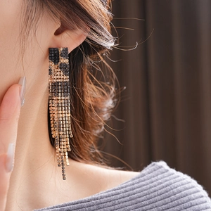 Close-up of leopard pattern tassel earrings with gold and black crystals on a model