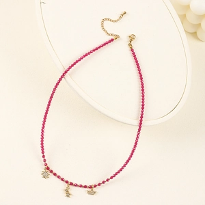 Detail of beaded necklace with rose red stones and gold star charms set with white zircon