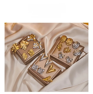 Dettaglio di orecchini vintage in acciaio inossidabile oro e argento su sfondo satin