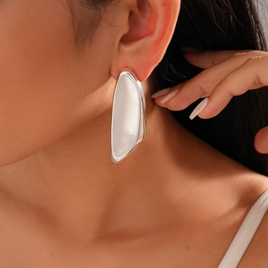 Close-up of a silver irregular geometric oversized earring with smooth metallic finish