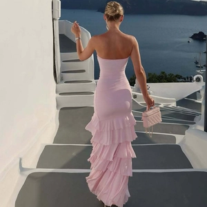 Detailed back view of a pink tiered ruffles maxi dress with high slit on Santorini cliff
