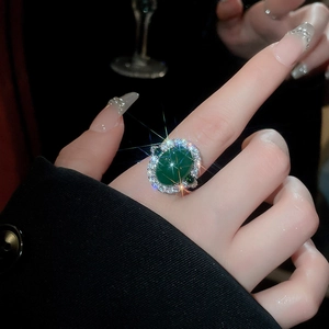 Détail d'une bague ajustable en zircon vert émeraude avec halo de diamants scintillants