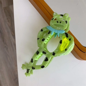 Detailaufnahme einer süßen grünen Frosch-Haarklammer mit schwarzen Punkten und Strassaugen