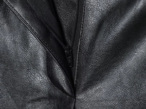 Detailed macro view of the metal zipper and fine stitching on black faux leather shorts