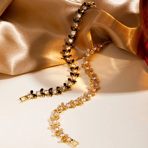 Macro detail of marquise-cut tennis bracelets in gold plating on elegant silk fabric
