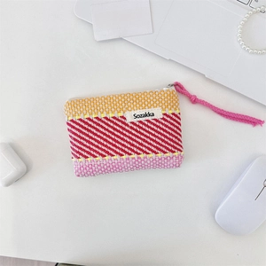 Detail of colorful woven stripe cosmetic pouch with brand label on a desk setup