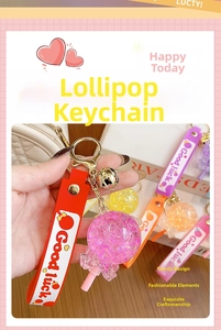 Luminous glitter lollipop keychain with Good Luck strap and bell on a checkered bag