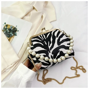 Detail view of zebra print clasp bag featuring pearl handle and gold chain strap