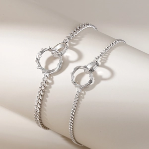 Minimalist silver Mobius thorn couple bracelets with interlocking rings on a clean pedestal