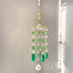 Detail of K9 crystal suncatcher with green faceted drops on a golden metal frame
