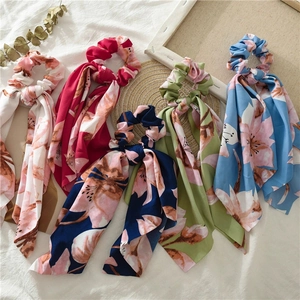 Flat lay of five floral satin hair scrunchies with long streamers on a white background
