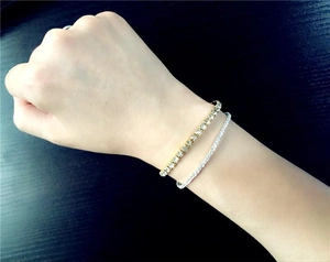 Close-up of gold and silver elastic rhinestone tennis bracelets on a person's wrist