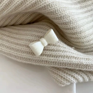 Gros plan d'une pince à cheveux nœud en velours blanc montrant la texture douce peluche