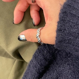 Close-up of minimalist S925 sterling silver twist ring worn on thumb with detailed texture