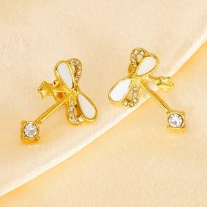 Elegant gold bow earrings with zircon and star details on silk background