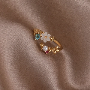 Detail of gold shell flower ring with pearl and heart gemstone on silk background