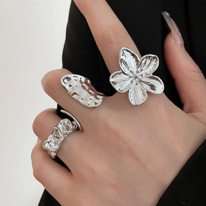 Detail view of silver floral and lava textured rings on a model with premium style