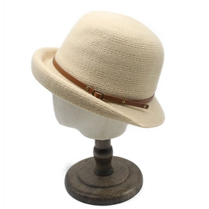 Détail du chapeau cloche en tricot beige avec lanière en cuir brun et boucle métallique