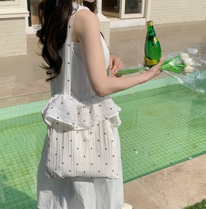 Close-up of white floral embroidered tote bag with delicate ruffle trim edge details