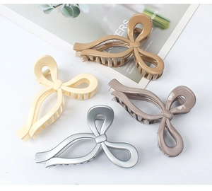 Detail of minimalist oversized bow hair claws in khaki, beige, and matte grey tones