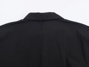 Detailed close-up of the black poplin shirt collar and neat stitching on the back
