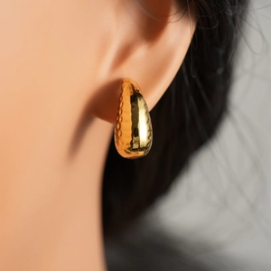 Detail of gold waterdrop earrings showing textured hammering and mirror polished finish