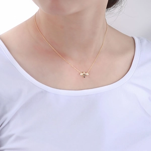Close-up of golden bee pendant necklace with white zircons on a model's neck