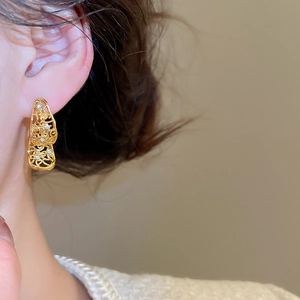 Gros plan de boucles d'oreilles vintage ajourées avec gravure et petits diamants