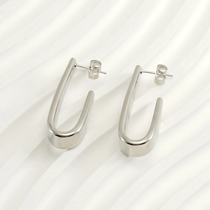 Gros plan de boucles d'oreilles en U argentées sur un fond blanc texturé