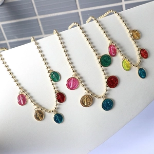 Detailed close-up of colorful enamel religious icons on golden beaded necklaces