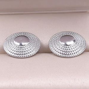Macro view of silver 304 stainless steel earrings with textured relief in a jewelry box
