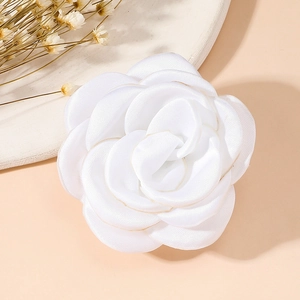 Detailed close-up of a white vintage silk flower brooch with elegant layered petals