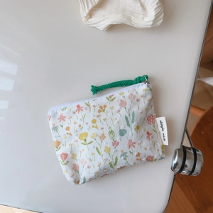 Detailed macro view of floral cotton coin purse with zipper and green woven puller strap