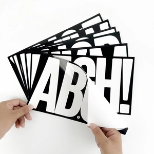Detail showing hand peeling a large adhesive 6-inch black and white letter A sticker