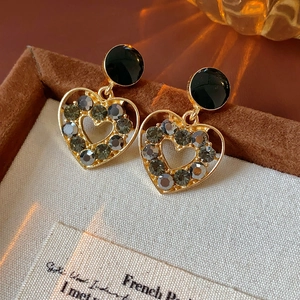 Gros plan sur des boucles d'oreilles cœur vintage avec strass gris sur daim marron