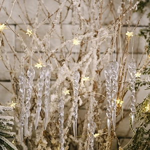 Macro shot of realistic clear icicle ornaments hanging on snowy branches with warm lights