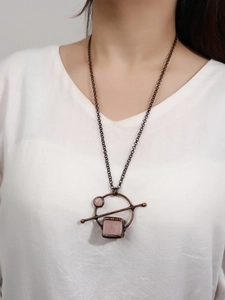 Close-up of vintage handmade rose quartz geometric pendant on a copper chain necklace