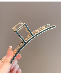 Close-up of golden shark hair clip with deep blue rhinestones in a sleek design