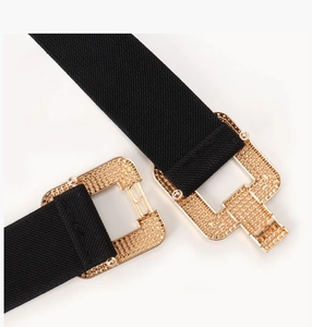 Close-up of black elastic waist belt with gold textured interlocking rectangular buckle