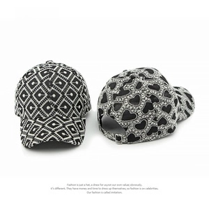 Detail of black and white baseball cap with diamond pattern and heart chain embroidery