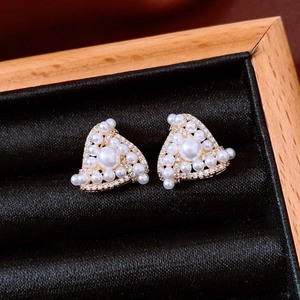 Macro view of gold plated triangle earrings featuring clustered white pearls and tiny zircons