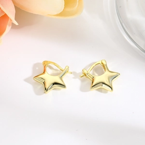 Detail of hollow star-shaped gold hoop earrings in minimalist polished copper design