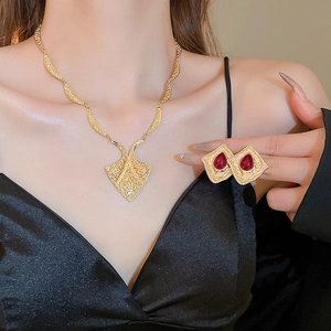 Close-up of vintage gold necklace and red gemstone earrings set on female model