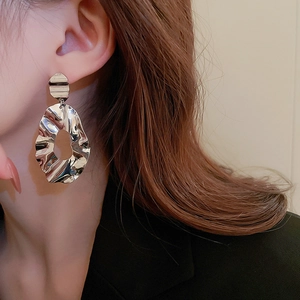 Close-up of model wearing silver textured irregular geometric hoop earrings with hollow design