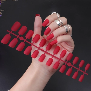 Macro shot of long square matte red false nail tips strip with frosted texture detail